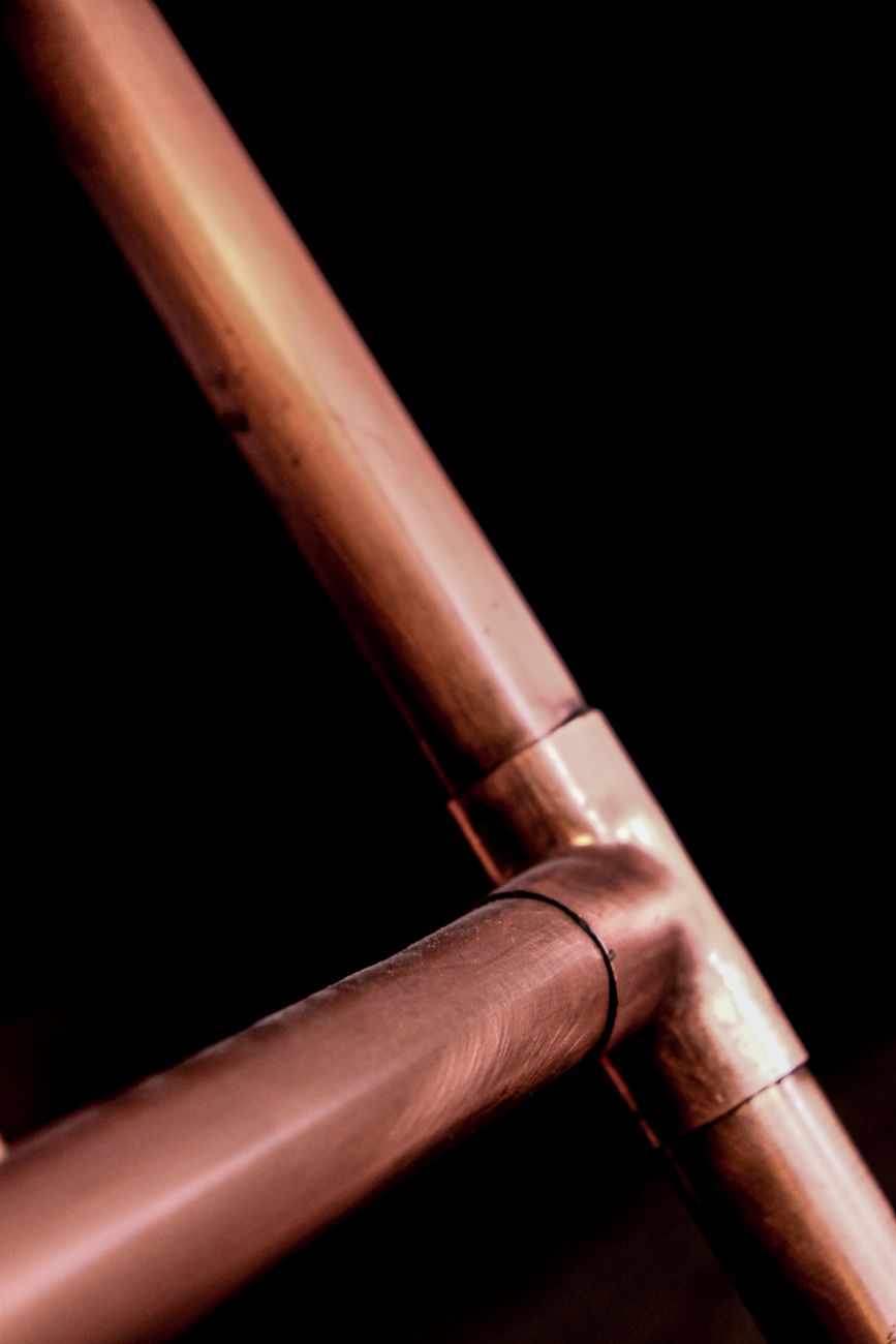 Copper pipework joint against a black background