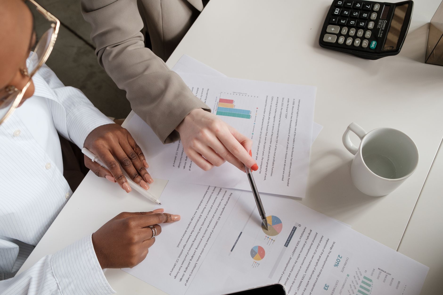 Hands pointing at charts on printed reports during a working session