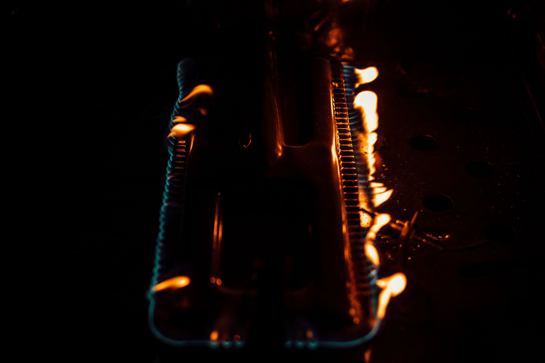 Lit gas burner glowing in a dark heater cabinet