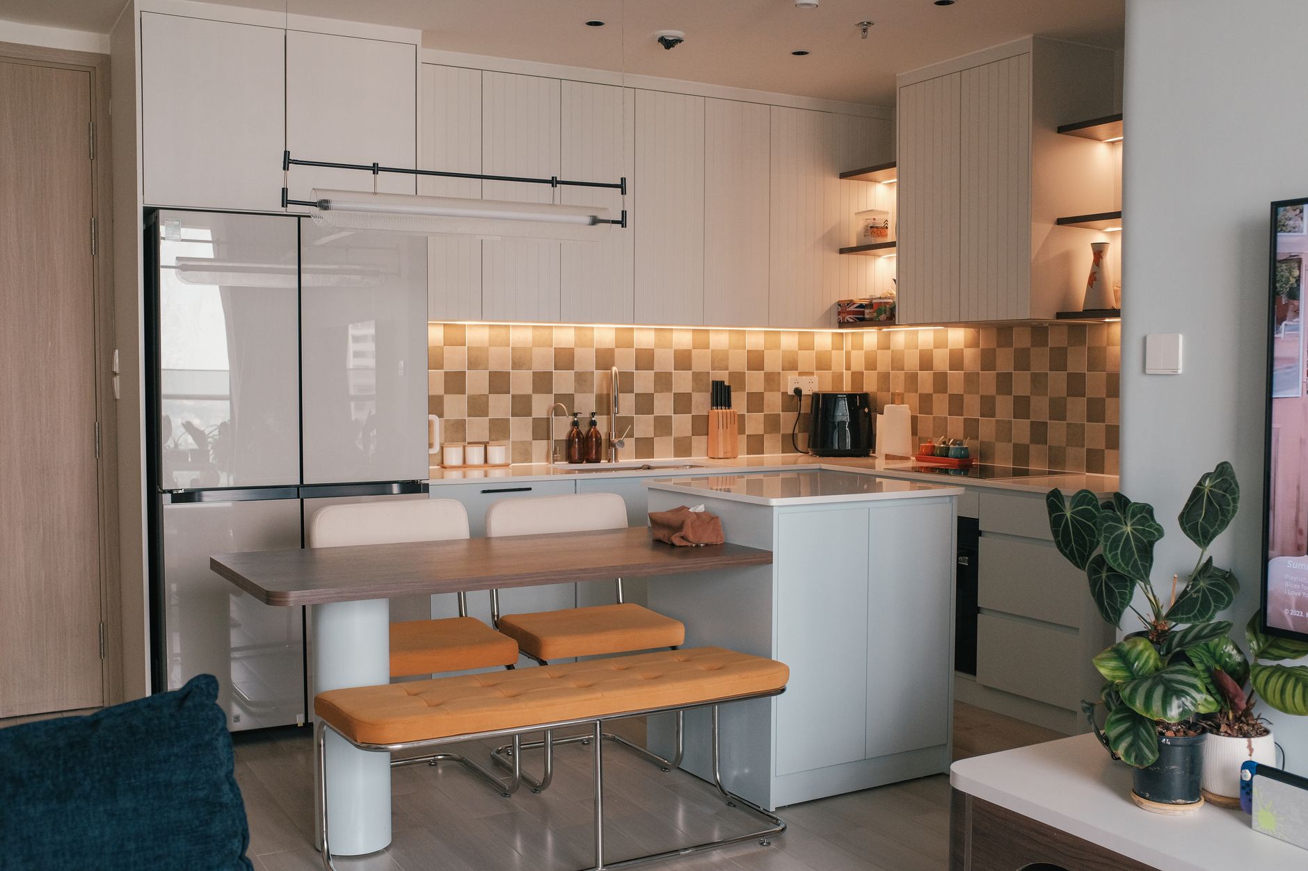 A warm kitchen with a chequered tile splashback and leather bench seating at the island