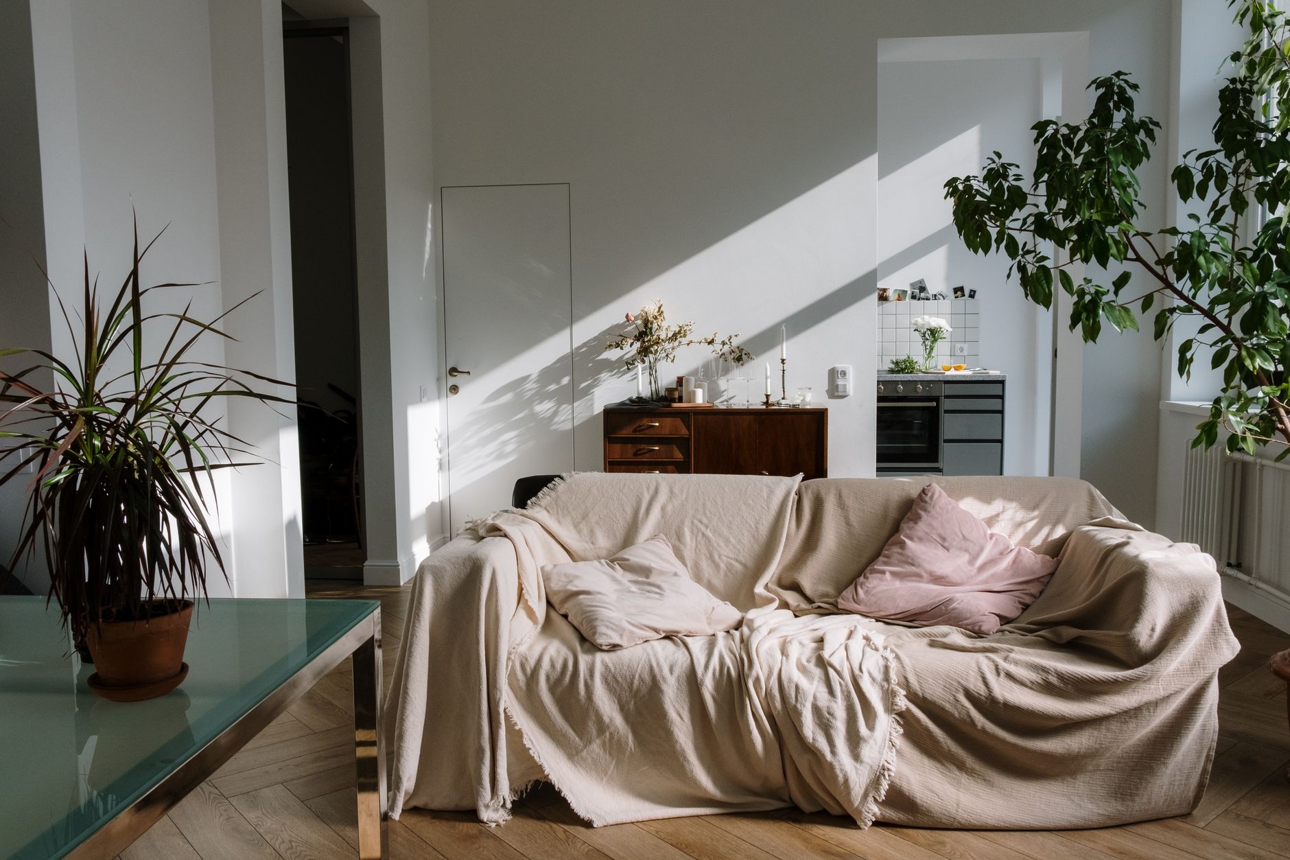 Morning sun falling across a linen-draped sofa in a lived-in lounge room