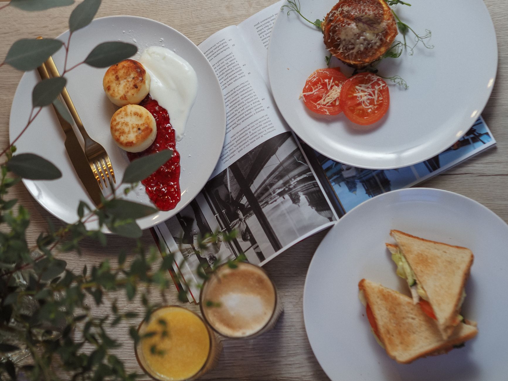 Shared brunch plates, coffee and juice laid out across a pale timber table