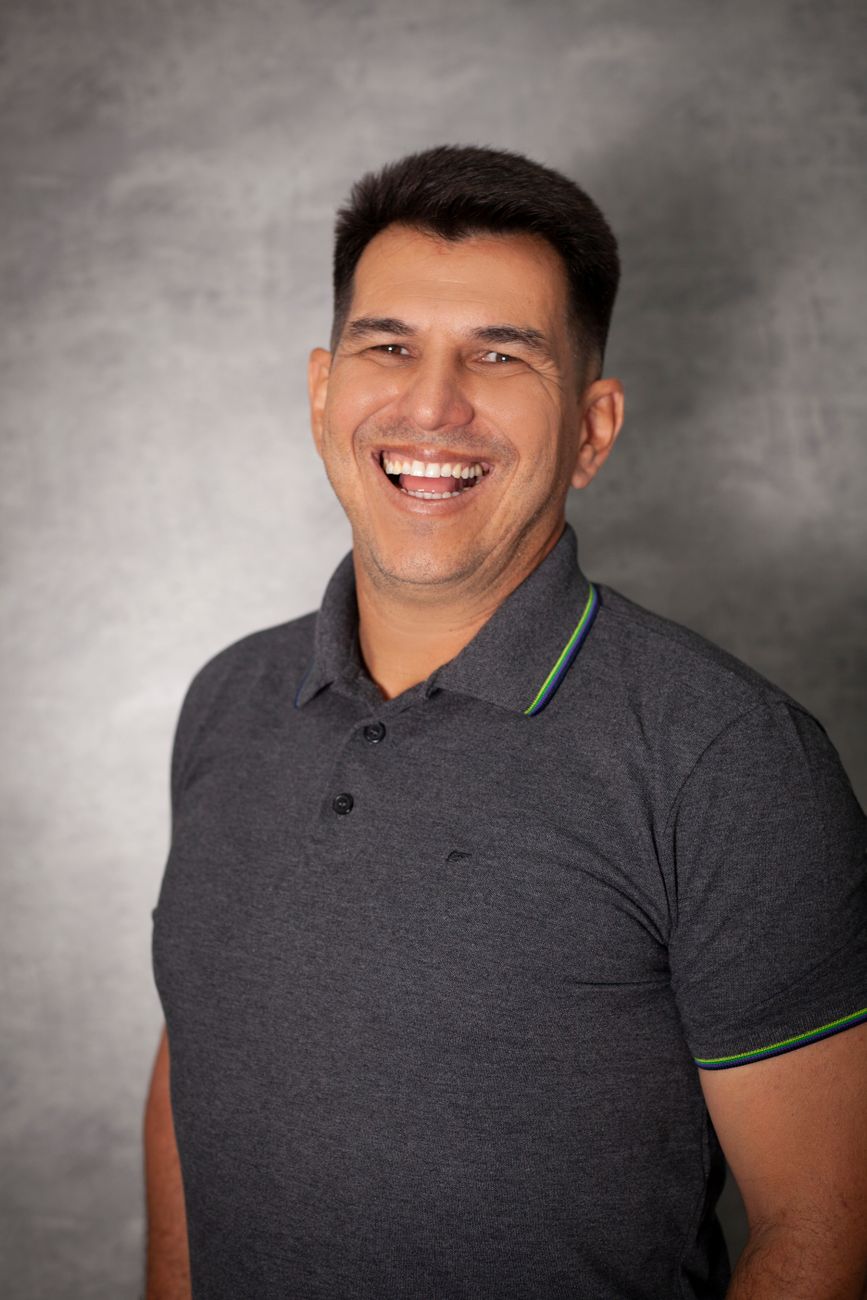 Portrait of a physiotherapist laughing warmly against a grey studio backdrop