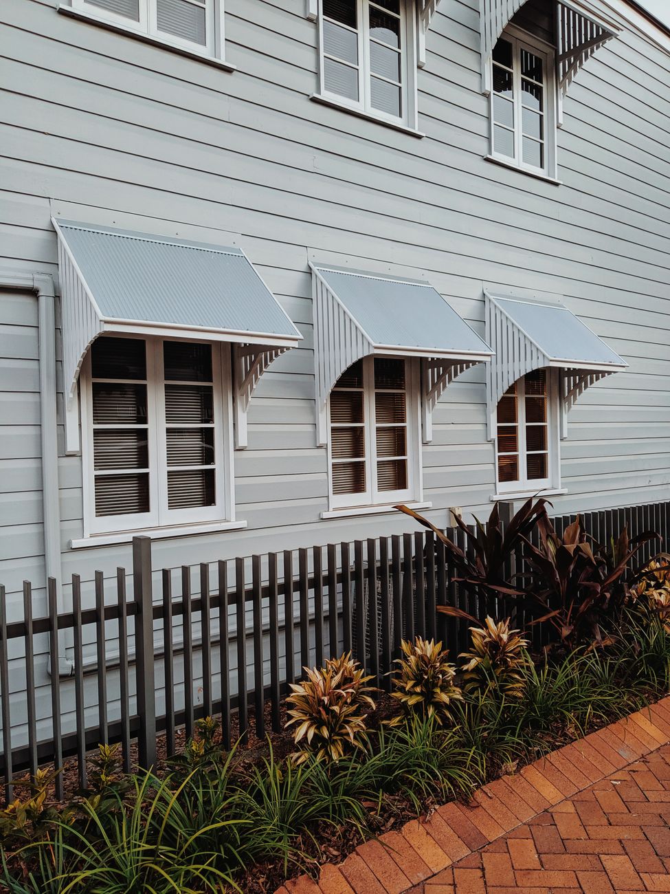 Warm light in the windows of a weatherboard home with corrugated awnings at dusk