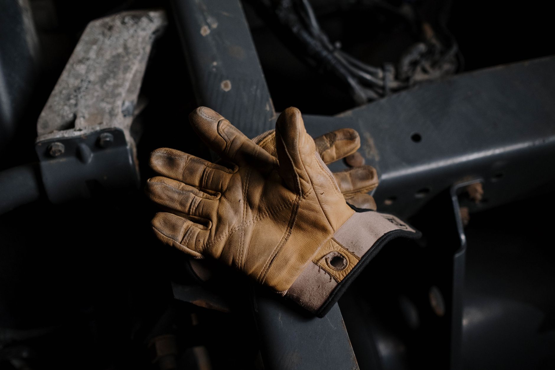 Worn leather work gloves resting on machinery